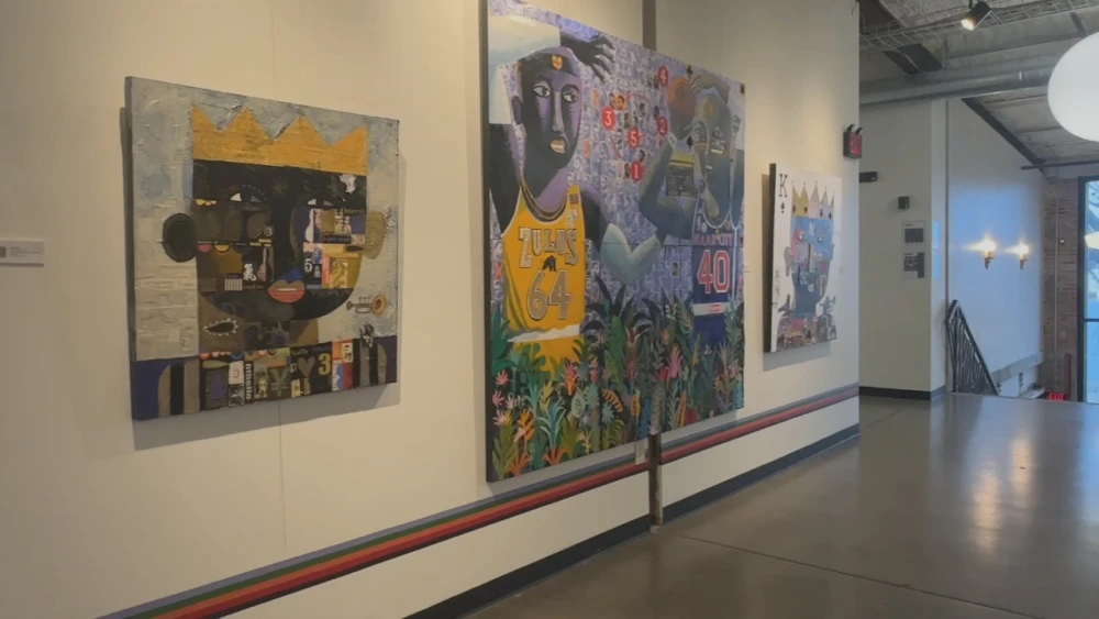Skip Hill paintings exhibited in the WOMPA gallery, including a large mixed-media painting with two basketball-jersey figures