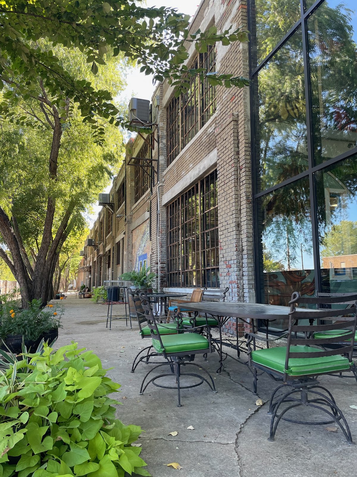 Green chairs and tables arranged near trees outside WOMPA