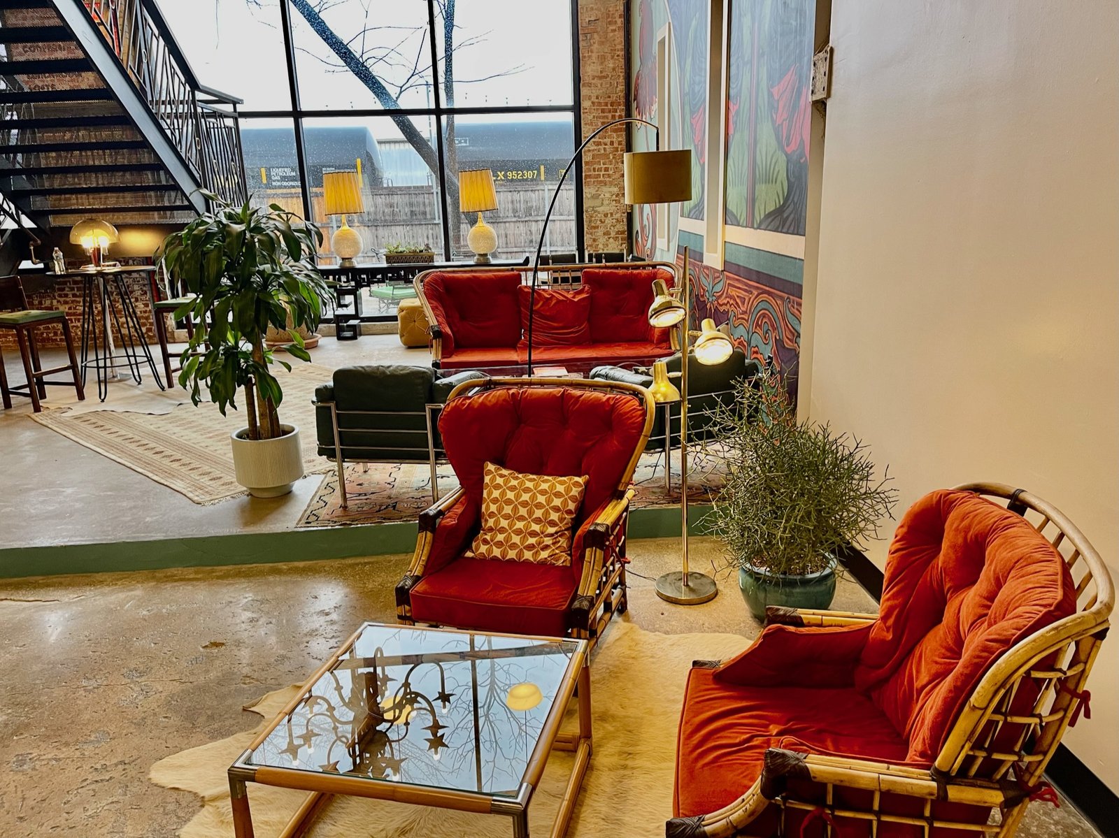 Vintage upholstered chairs and a glass table near a WOMPA lounge window