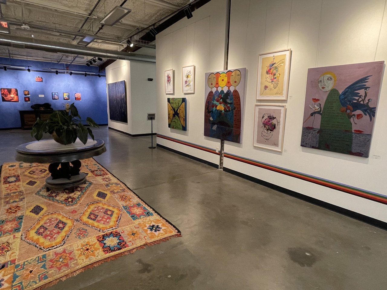 An art gallery at WOMPA with framed paintings exhibited on white walls